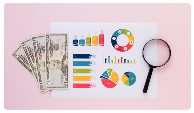 Cash, pie charts, and a magnifying glass laid out on a pink background